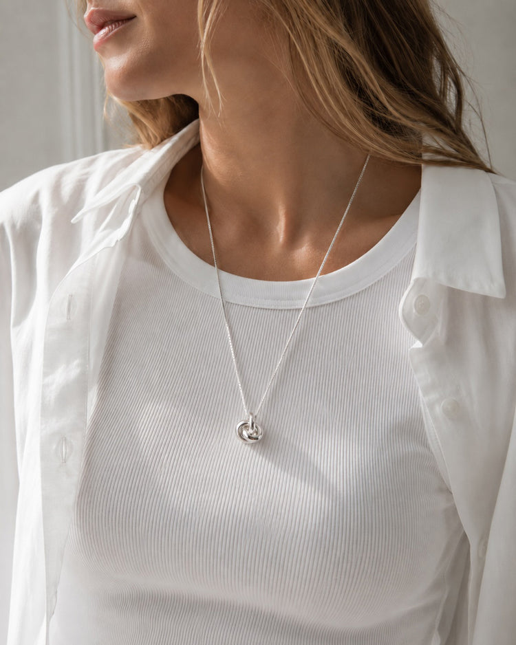 Kvinna som bär ett halsband med en silverknut i kedja.