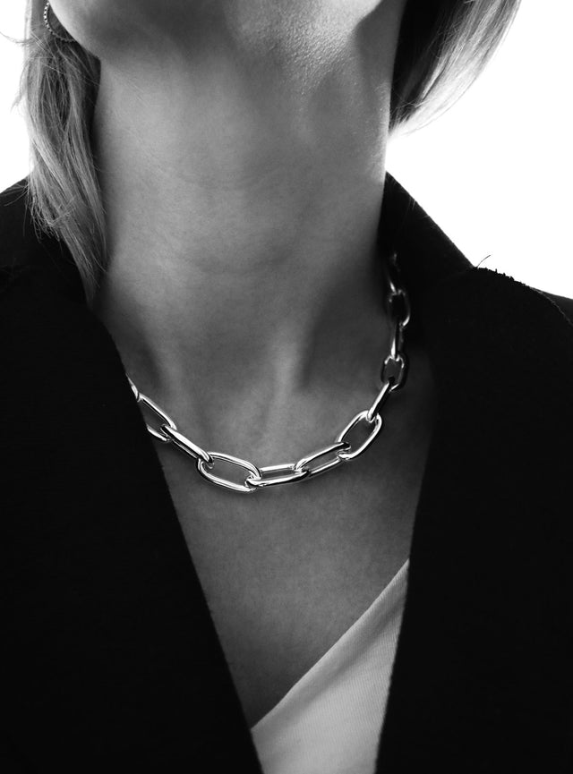 Tjej som bär en stor silverkedja runt halsen med ovala länkar - Paperclip kedja. 