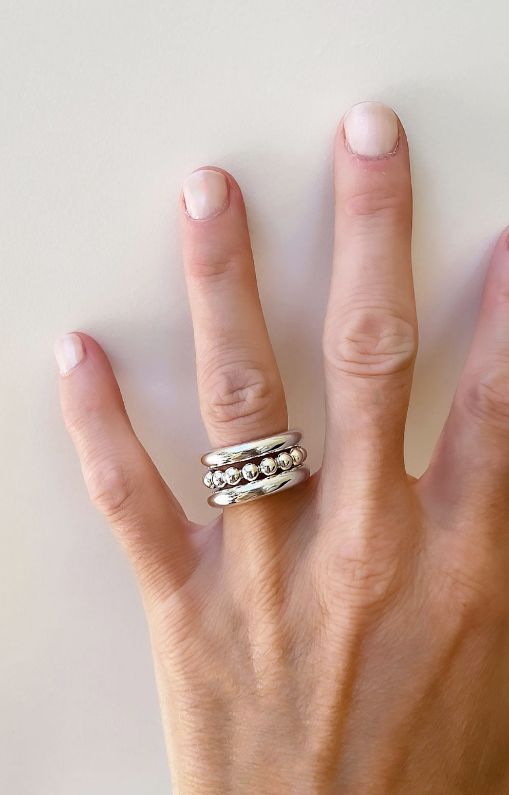 tre tjocka silverringar i kombination. två släta ringar och en ring med kulor i mitten.