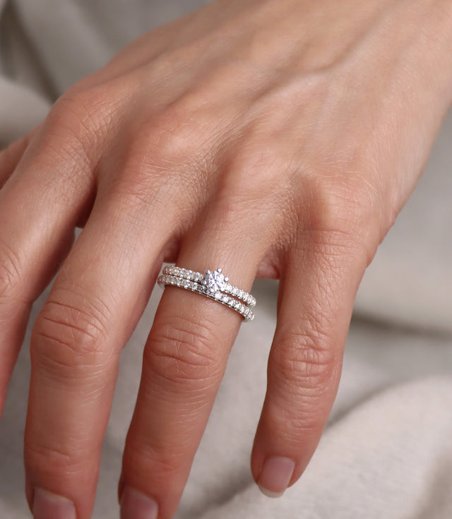 Kvinna som bär ett set med vigselring och förlovningsring. Diamantringar med band av diamanter. 