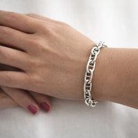 Kvinna som bär ett armband med silverkedja - modell bred Ankarkedja. 