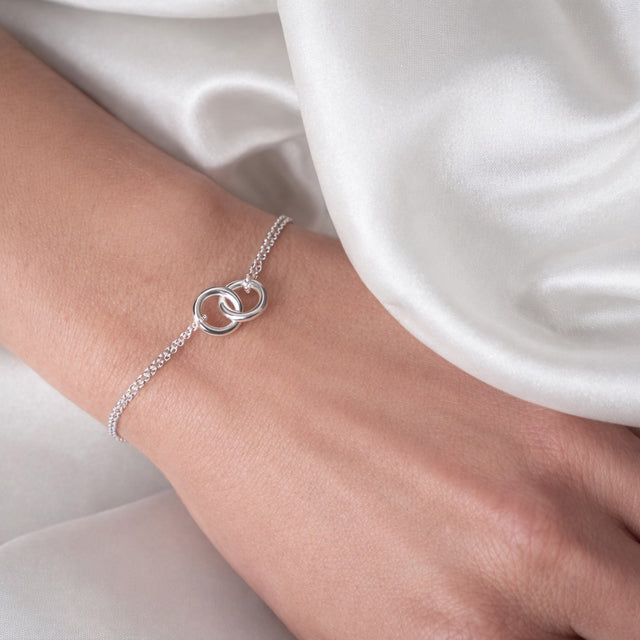 Tjej som bär ett silverarmband med två ringar i dubbla kedjor. 