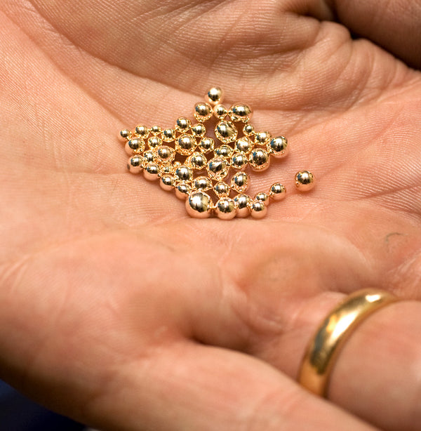 Små kulor av återvunnet guld i handflata