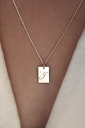 Tjej som bär ett halsband med bokstavsberlock i silver med liten diamant