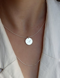 Tjej som bär ett bokstavshalsband med berlock i silver med bokstav + diamant. 