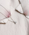 Närbild på halsband med briljantslipad diamant från Mila Silver placerad på en stor snäcka. 