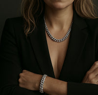 Kvinna som bär ett brett kedjehalsband med matchande armband i silver. Kedjemodell: Pansarkedja. 