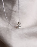 Hängsmycke med diamant i rörfattning sett från sidan. 