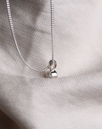 Hängsmycke med diamant i rörfattning sett från sidan. 