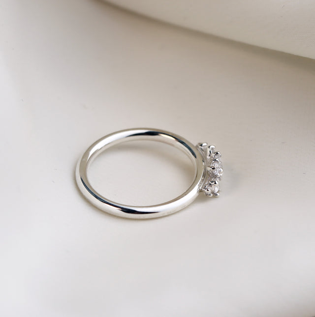 Diamantring i silver, sett från sidan. Ringen har diamanter infattade i kronor. 