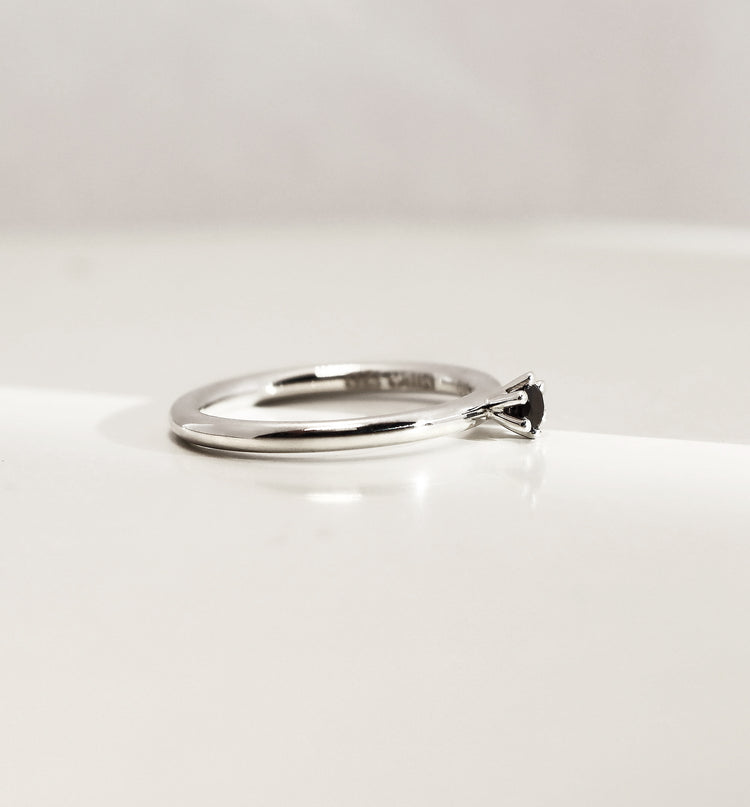 Silverring med svart diamant, sedd från sidan. Diamanten är infattad i krona. 