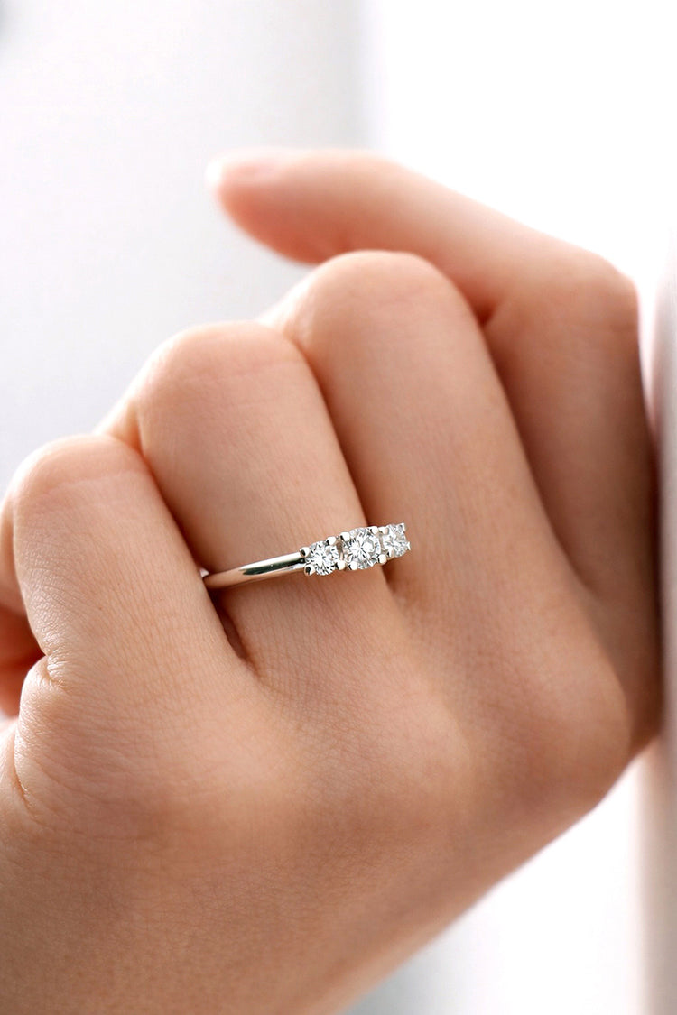 Kvinna som bär förlovningsring med tre diamanter. 