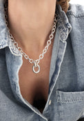 Kvinna som bär ett chunky kedjehalsband i silver. 