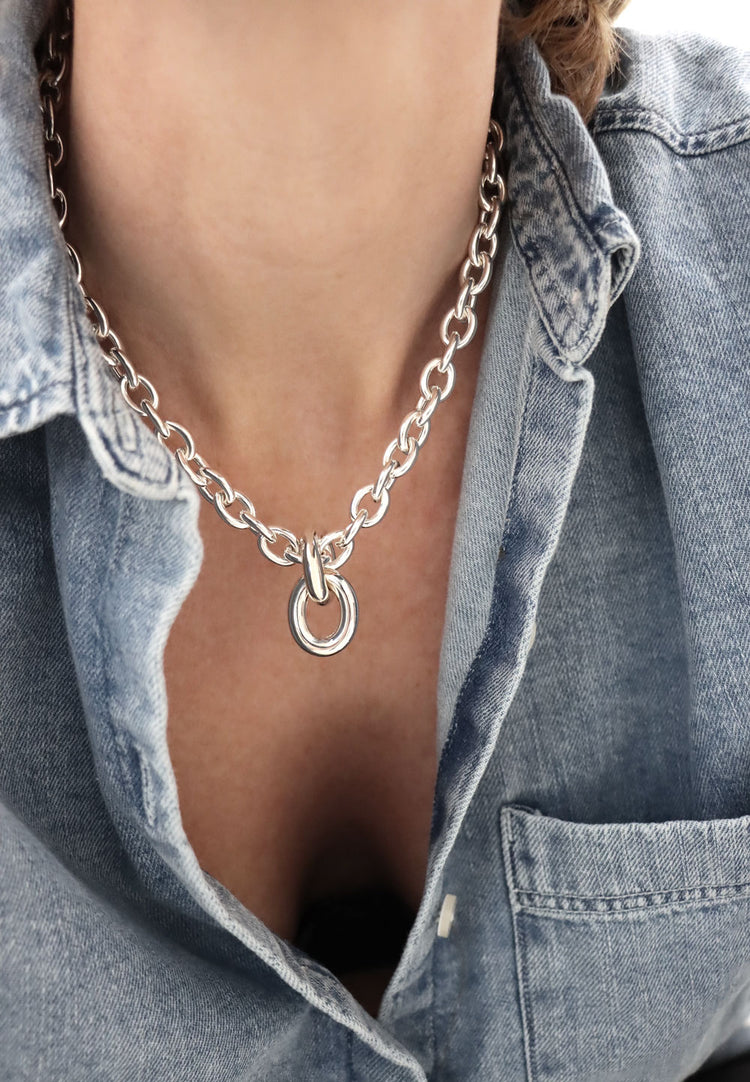 Kvinna som bär ett chunky kedjehalsband i silver. 