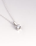 närbild på ett hängsmycke med gnistrande diamant i fyrkantig fattning. 
