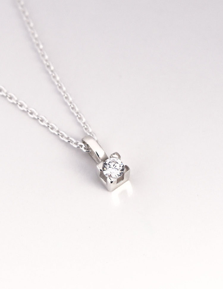 närbild på ett hängsmycke med gnistrande diamant i fyrkantig fattning. 