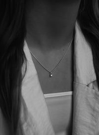 Svart-vit bild på en tjej som bär ett kort diamanthalsband med berlock i kedja. 