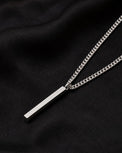 Silverstav i kedja - halsband till herr, placerat på ett svart tyg. 