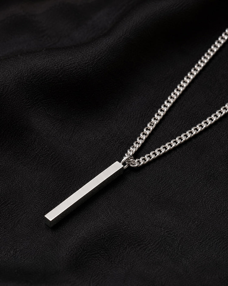 Silverstav i kedja - halsband till herr, placerat på ett svart tyg. 