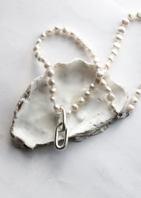 Pärlhalsband som ligger på ett stort snäckskal