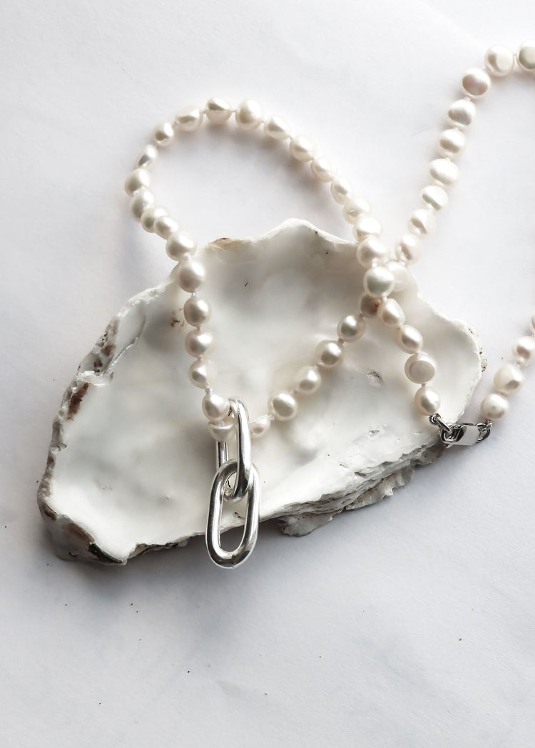 Pärlhalsband som ligger på ett stort snäckskal