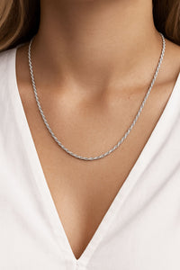 Silverhalsband på en kvinna med Rope kedja, bärs till urringad vit blus. 