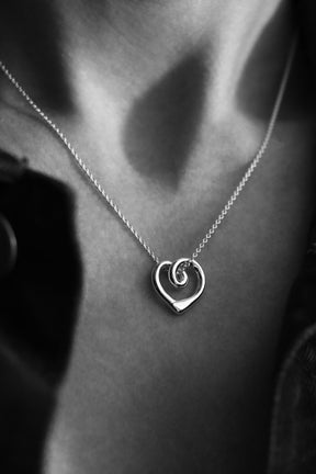 Närbild på ett silverhalsband med ett hjärta som hänger i en silverkedja. 