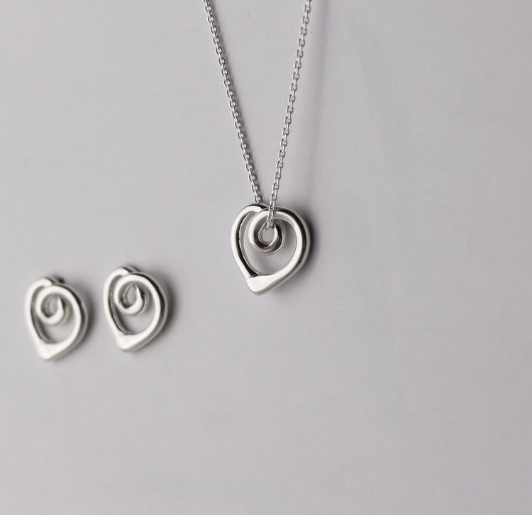 Silverhalsband med ett hängsmycke utformat som ett hjärta med organiska former, sett från sidan. 