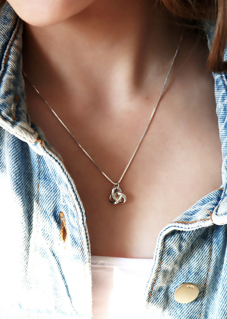 Tjej som bär ett silverhalsband med massiv silverknut. 