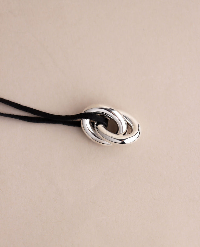 två länkar i silver i svart läderband. 