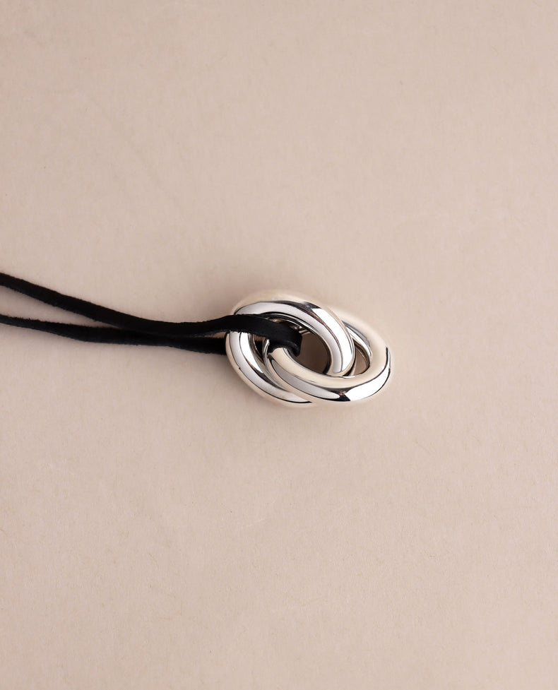 två länkar i silver i svart läderband. 