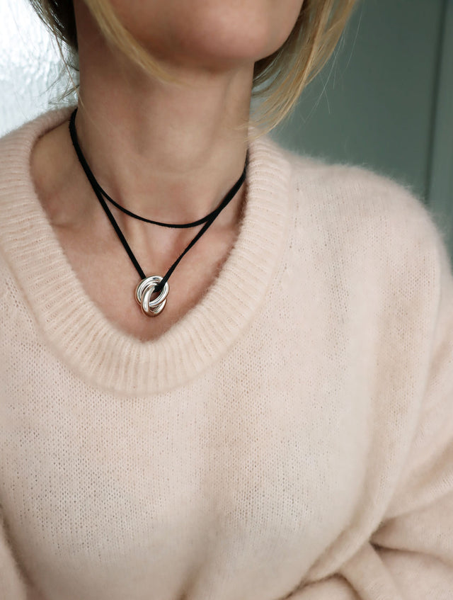 Tjej som bär ett choker halsband med svart läderband och två tjocka länkar. 