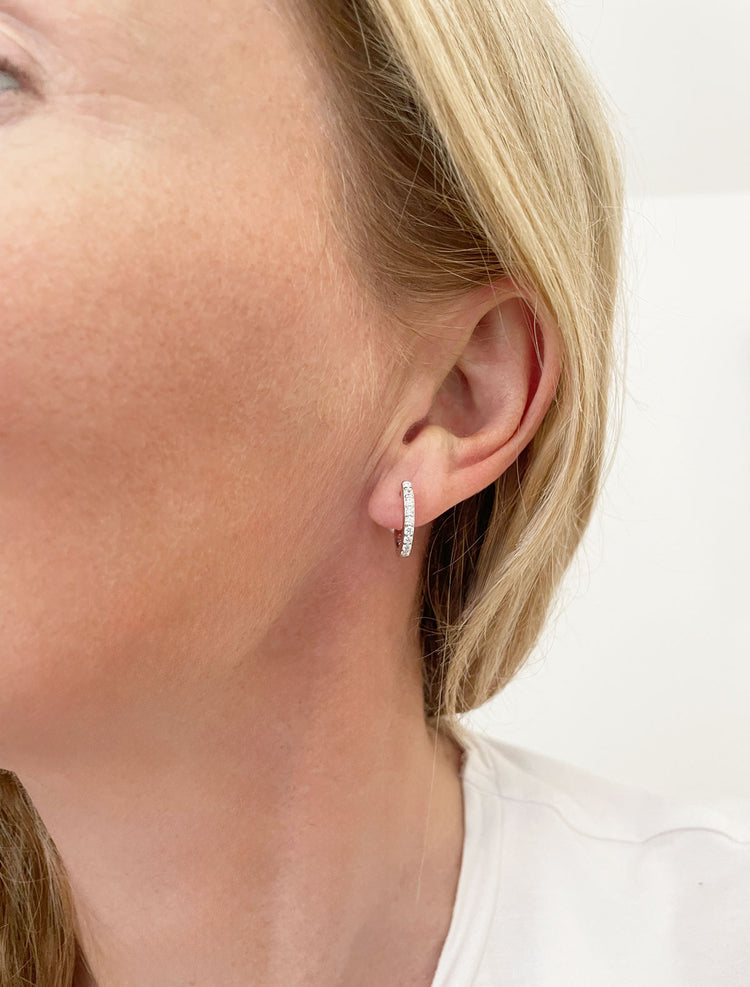tjej som bär ett litet hoop örhänge i silver med diamanter. 