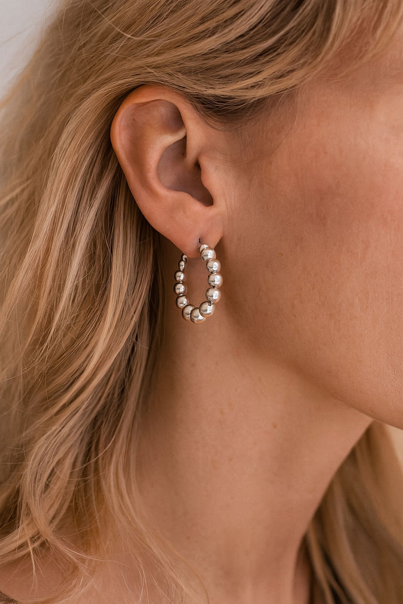 Örhängen med ringar och silverkulor på en tjej. 