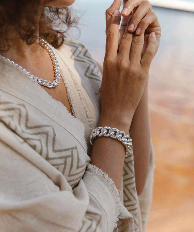 Kvinna på stranden som bär ett brett kedjearmband  silver med matchande kedjehalsband