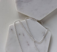 en kulkedja i silver som ligger på två marmor block. 