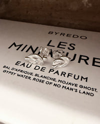 Örhängen med silverknutar ligger på vit ask från parfume märket Byredo. 