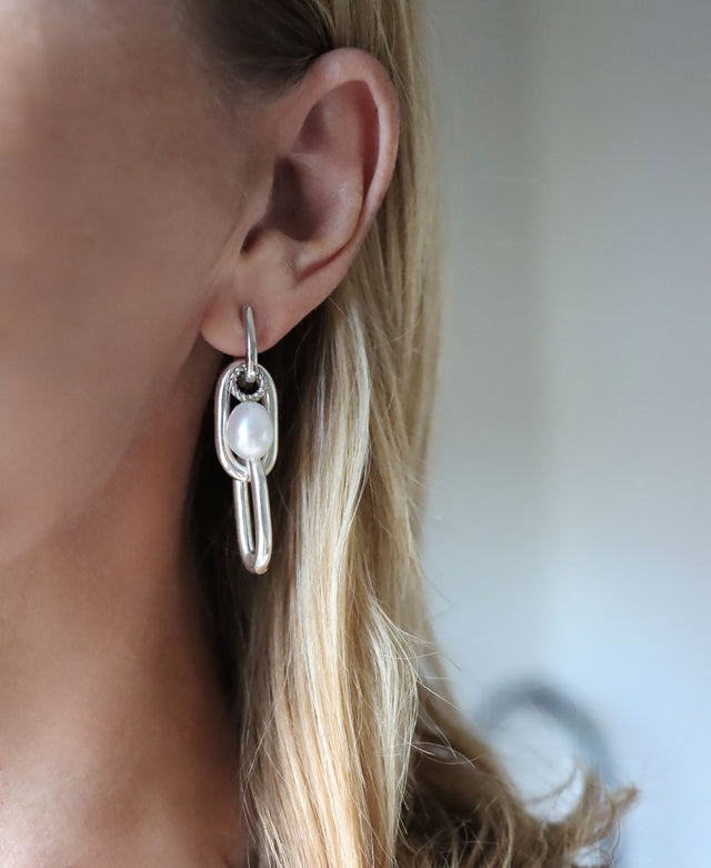 Tjej som bär hängande silverörhängen med kedjor och pärlor. 