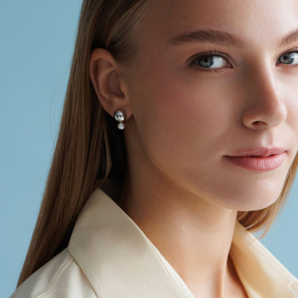 Kvinna som bär ett par silverörhängen med pärlor. 