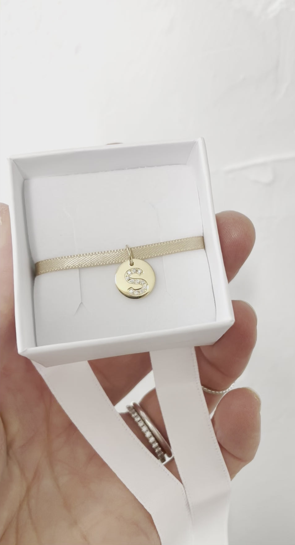 Bokstavsberlock i guld med diamanter som visas i presentask.