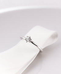 Diamantring i silver med en briljantslipad 0,25 ct diamant placerad runt ett vitt sidenband. 