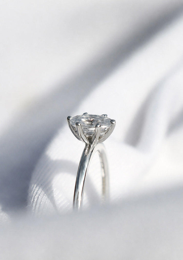 Ring i vitguld med oval diamant i 6-klo fattning sedd från sidan. 