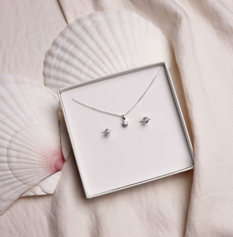 Ett set med matchande diamantsmycken placerade i en vis ask som ligger på två stora vita snäckor. 