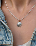 Tjej som bär ett halsband med silversnäcka i kedja. 