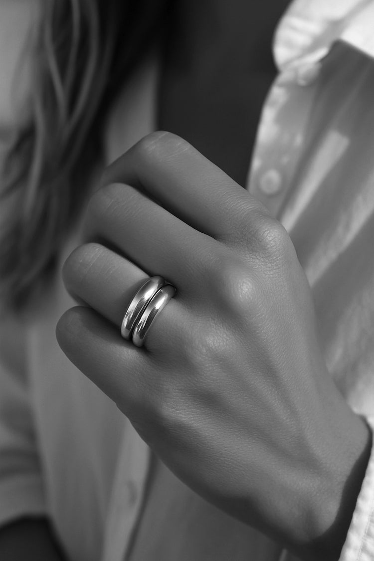 Tjej som bär en ring stack med två tjocka silverringar. 
