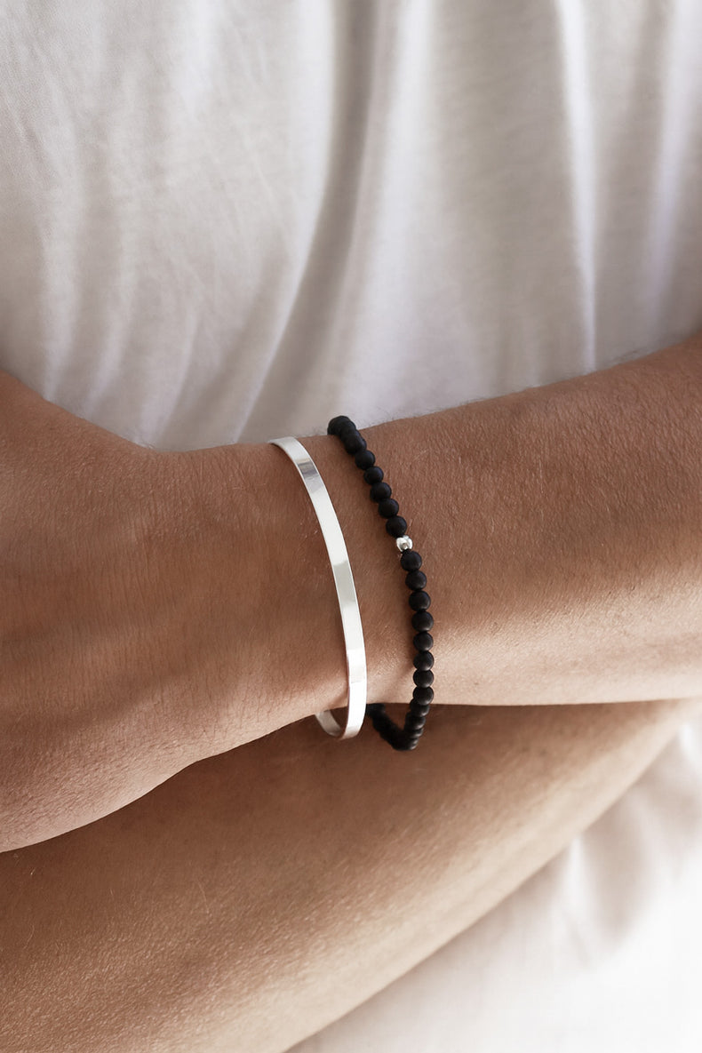 Man som bär ett stelt silverarmband i äkta silver. 