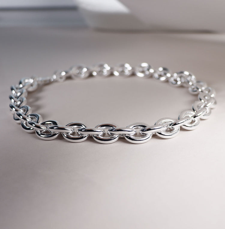 Närbild på ett brett kedjehalsband med ovala tjocka länkar. 