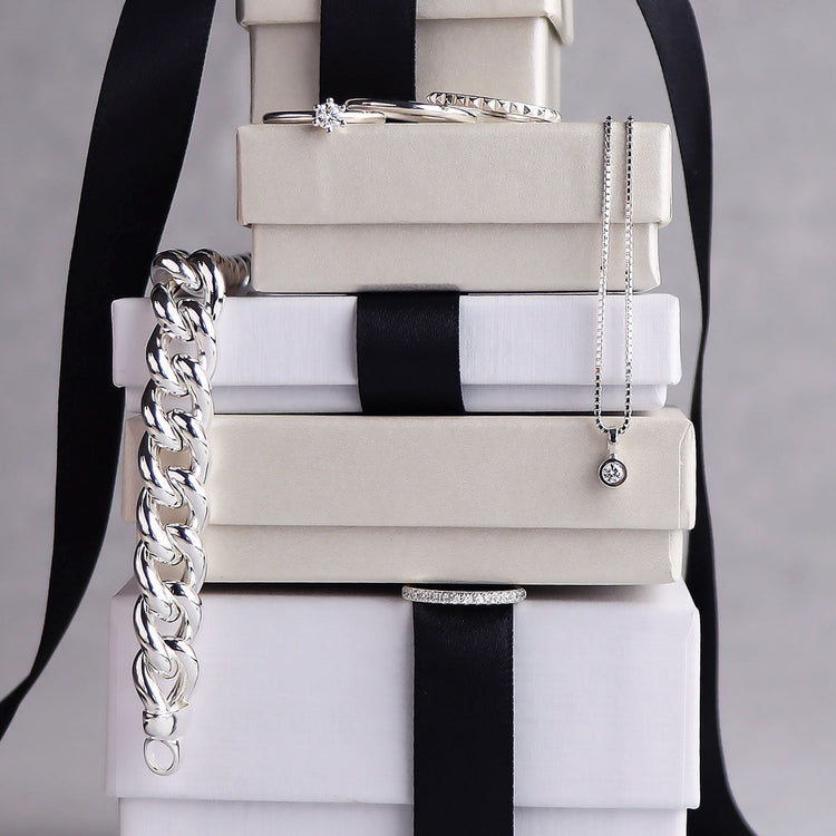 En stapel med present-askar där silversmycken är placerade mellan askarna. 