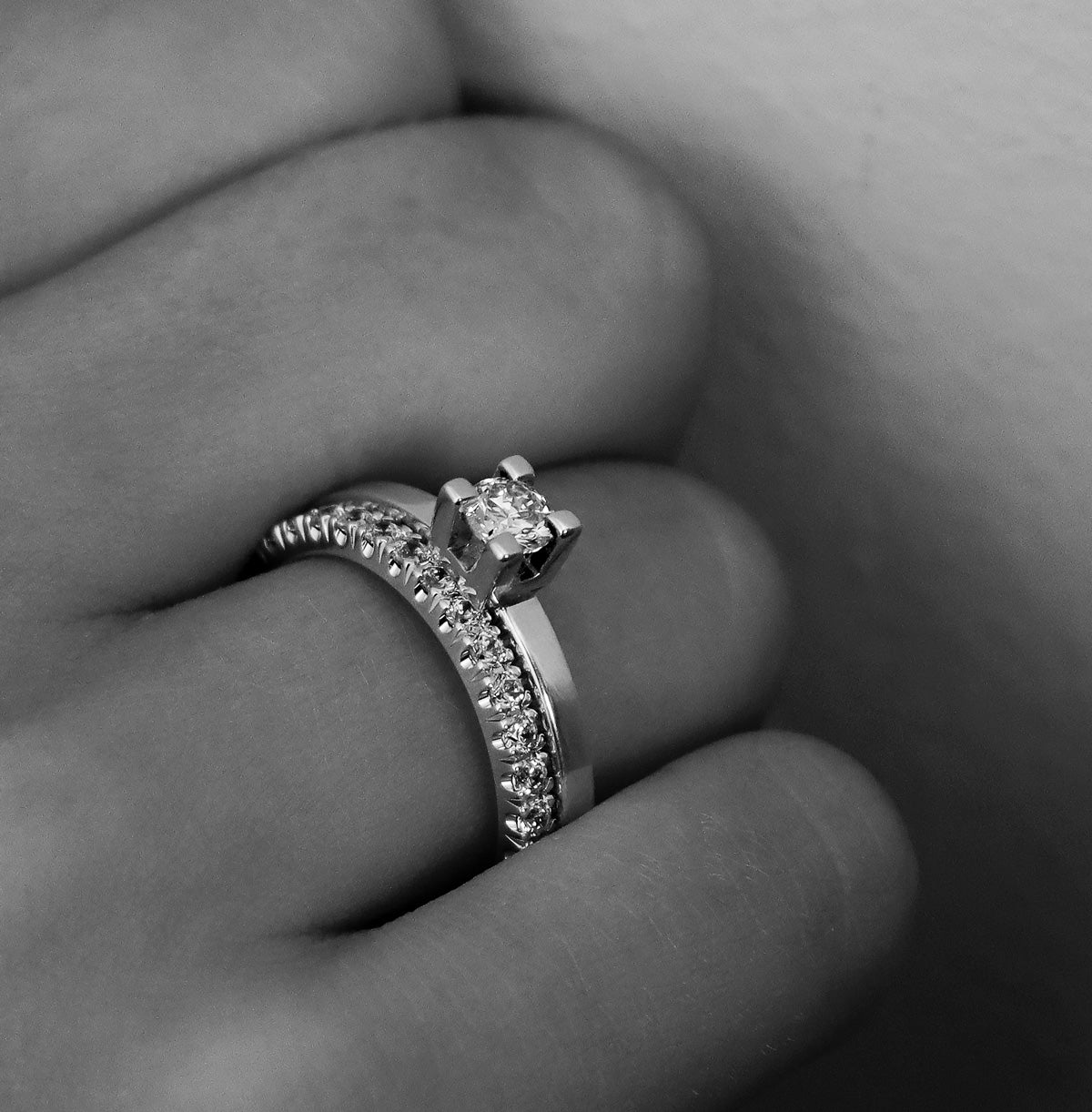 Två diamantringar i ett set som bärs på ett ringfinger. Alliansring + solitärring med raka profiler och gnistrande diamanter. 
