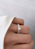 Kvinna som bär ett set med vigsel- och förlovningsring i silver. En alliansring med flera diamanter på rad och en solitärring med en 0,25 ct diamant. 